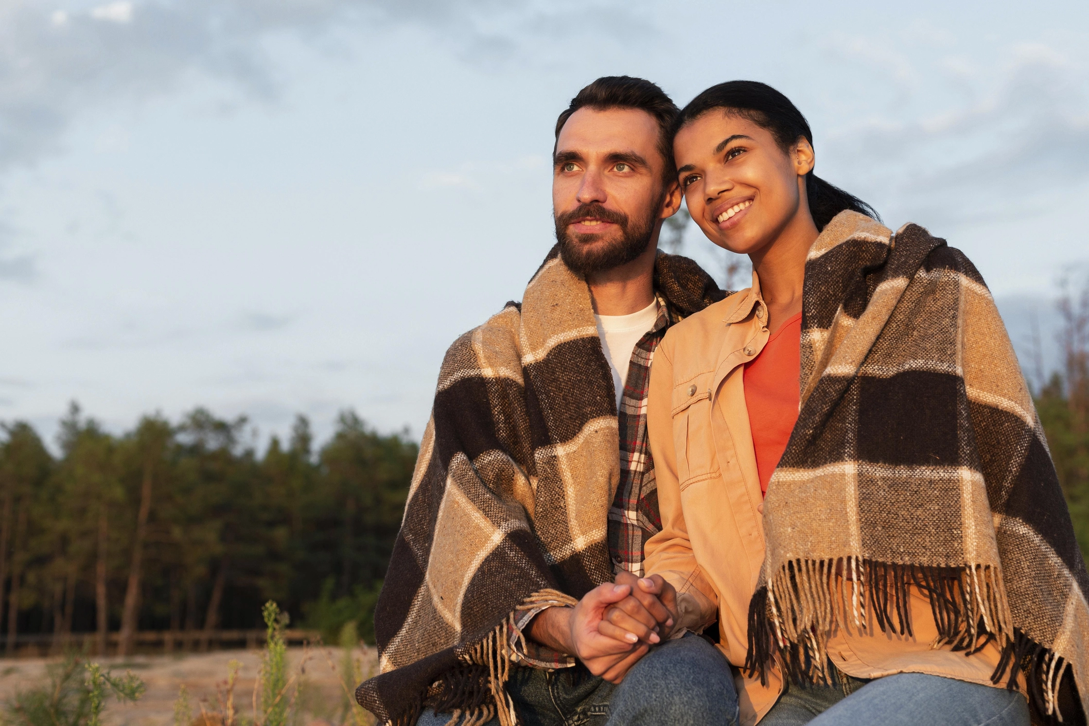 couple-looking-sunset-while-being-covered-with-blanket