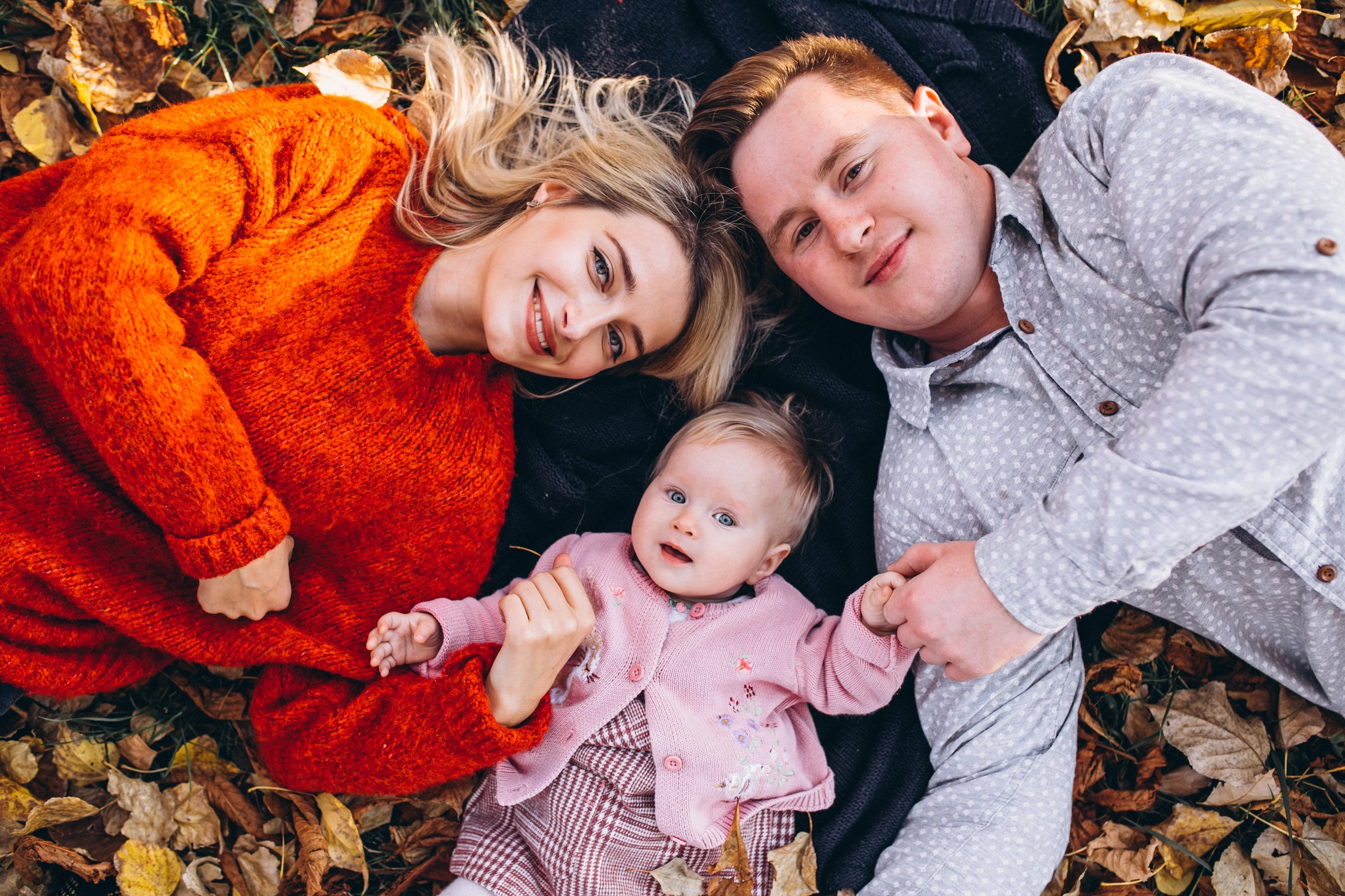 family-with-baby-daugher-lying-leaves-park