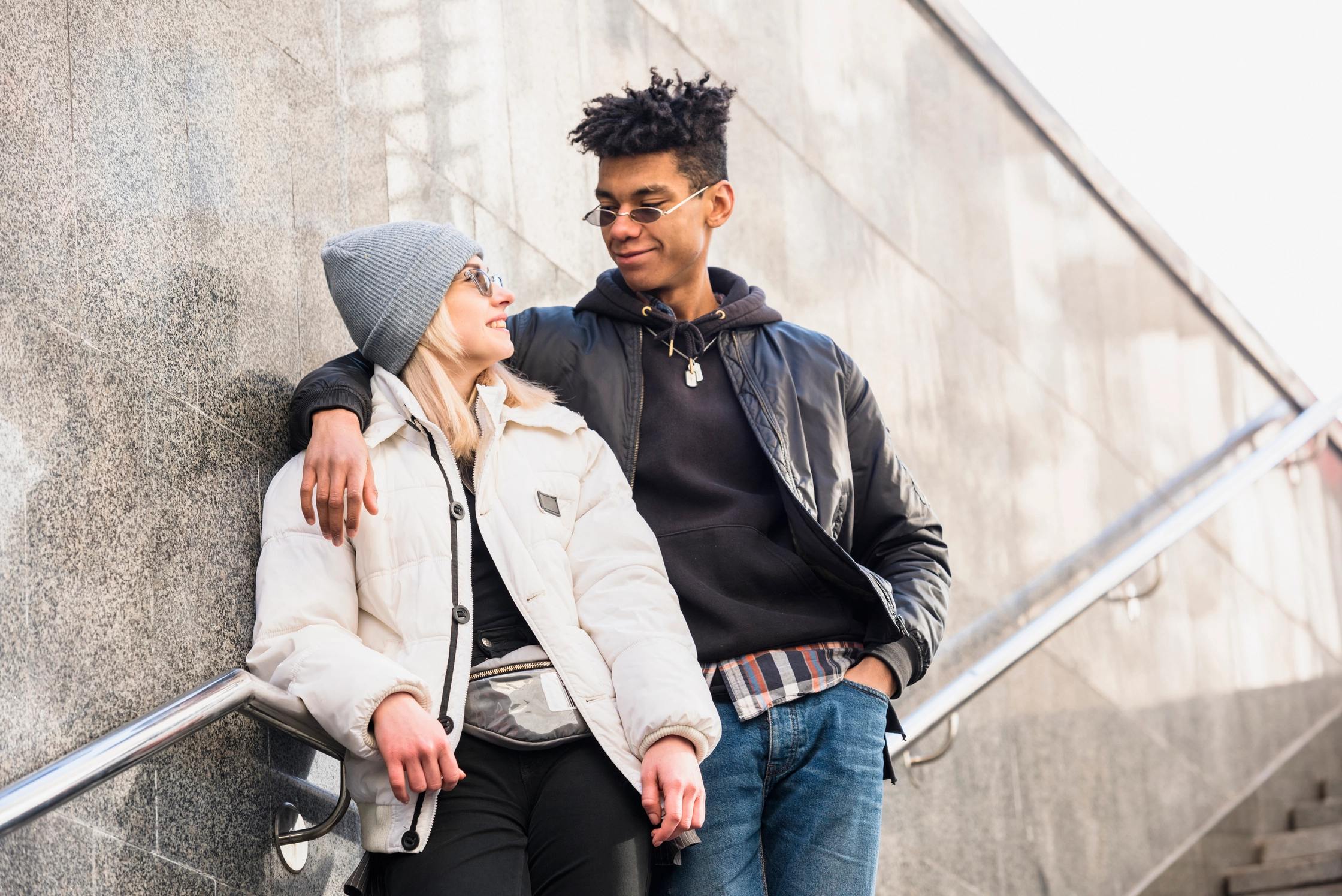 modern-interracial-young-couple-wearing-sunglasses-standing-staircase-looking-each-other